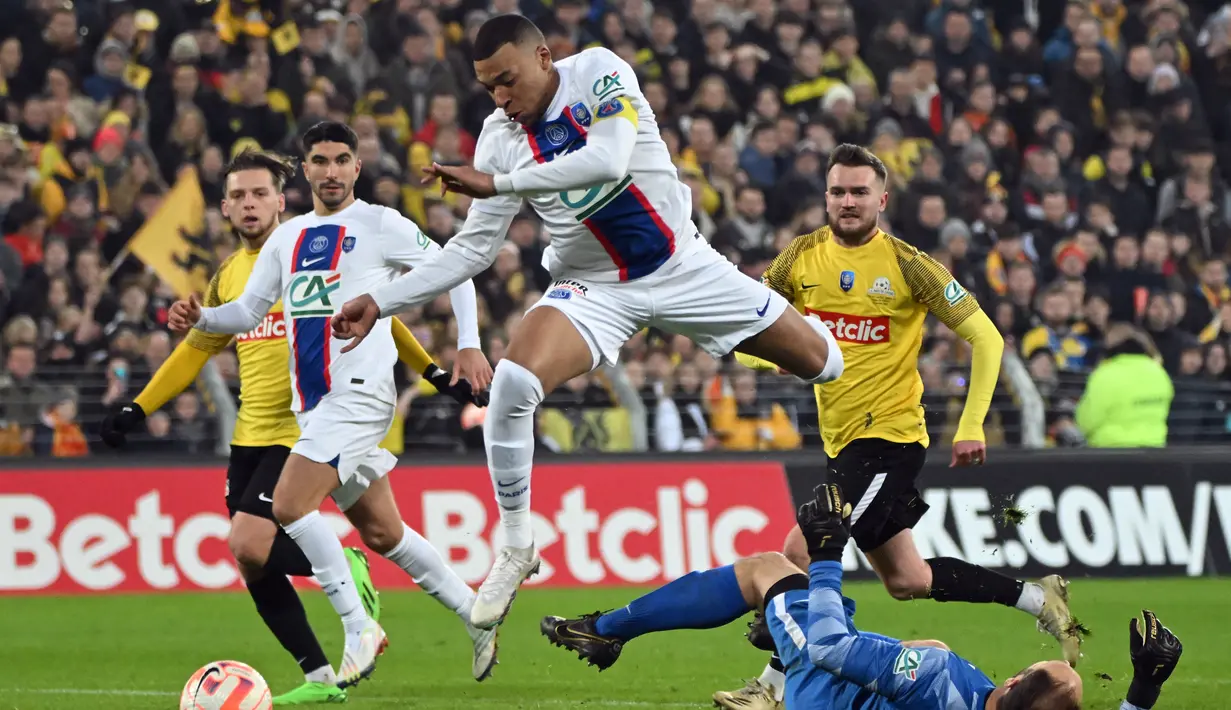 Kylian Mbappe melompati kiper Pays de Cassel Romain Samson untuk mencetak gol selama pertandingan babak 32 besar Piala Prancis di stadion Bollaert-Delelis di Lens, Prancis pada 23 Januari 2023. Striker Prancis itu sudah mencetak hat-trick di babak pertama. (AFP/Francois Lo Presti)