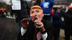 Aksi penolakan Donald Trump sebagai Presiden AS di Washington DC, Jumat (20/1). Seorang demonstran memakai topeng berwajah mirip Trump dengan hidung yang dipanjangkan. (AFP PHOTO / Jewel SAMAD)