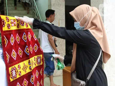 Petugas menyemprotkan cairan disinfektan ke sajadah jemaah sebelum Salat Jumat di Masjid El-Syifa, Jakarta, Jumat (20/3/2020). Sejumlah masjid di Jakarta masih menggelar salat Jumat meski ada imbauan dari MUI terkait merebaknya virus corona atau COVID-19. (Liputan6.com/Fery Pradolo)