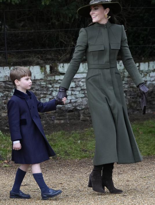 Kate Middleton, Princess of Wales dari Inggris mengandeng Pangeran Louis usai kebaktian Natal di Sandringham, Norfolk, Inggris pada 25 Desember 2022. Ia melengkapinya dengan topi bertepi lebar, juga berwarna senada, serta anting-anting chandelier dengan batu bernuansa hijau. (AP Photo/Kirsty Wigglesworth)