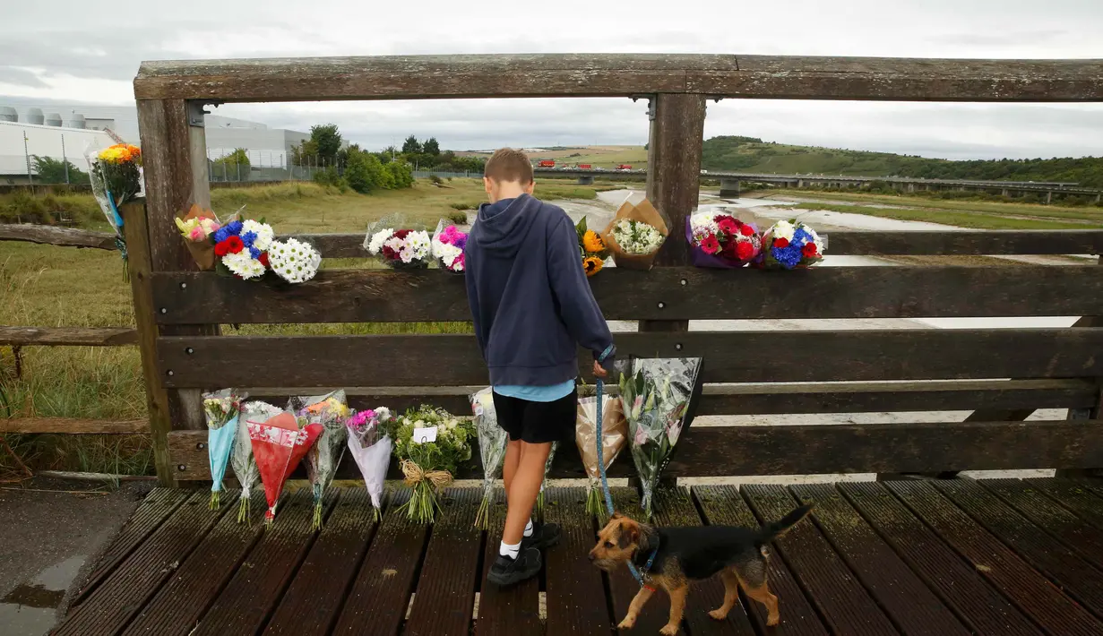 Seorang anak melihat bunga duka cita di dekat lokasi jatuhnya jet Hawker Hunter di Jalan Raya A27, Shoreham, Inggris, Minggu (23/8/2015). Pesawat yang tengah mengikuti Shoreham Airshow tersebut menewaskan sedikitnya  tujuh orang. (REUTERS/Luke MacGregor)
