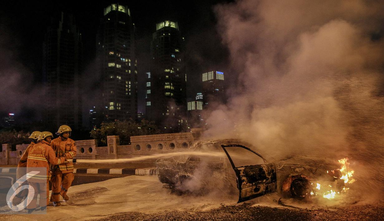 Petugas berusaha memadamkan api mobil yang terbakar di jalan layang Latuharhari, Jakarta, Kamis (18/9/2015). Diduga kebakaran akibat konsleting listrik yang terjadi dibagian depan kap mobil. (Liputan6.com/Faizal Fanani)