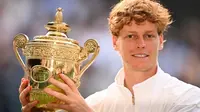 Jannik Sinner dari Italia merayakan kemenangannya dengan trofi juara sambil berpose untuk foto setelah kemenangannya melawan Carlos Alcaraz dari Spanyol di akhir pertandingan final tunggal putra pada hari&nbsp;ke-14 Kejuaraan Wimbledon 2025 di All England Lawn Tennis and Croquet Club di Wimbledon, London barat daya, pada 13 Juli 2025. (Kirill KUDRYAVTSEV/AFP)