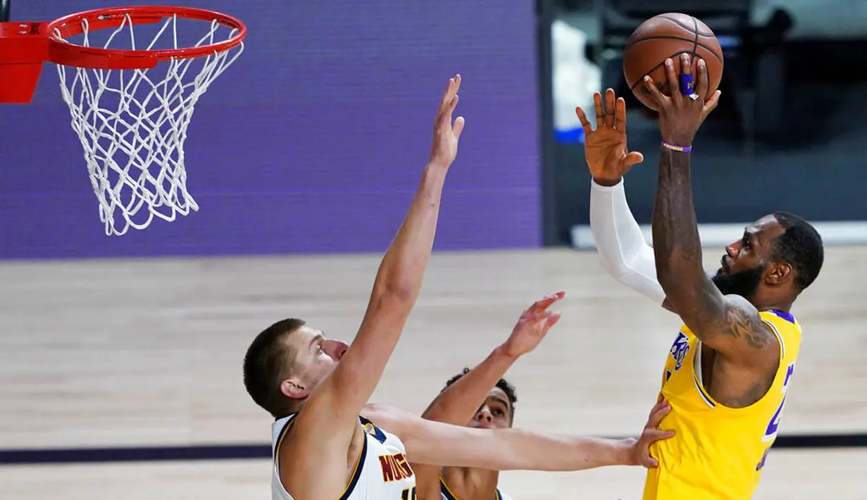 Pebasket Los Angeles Lakers, LeBron James, berusaha memasukkan bola saat melawan Denver Nuggets pada laga NBA di The Arena, Senin (11/8/2020). LA Lakers menang dengan skor 124-121. (AP Photo/Ashley Landis, Pool)