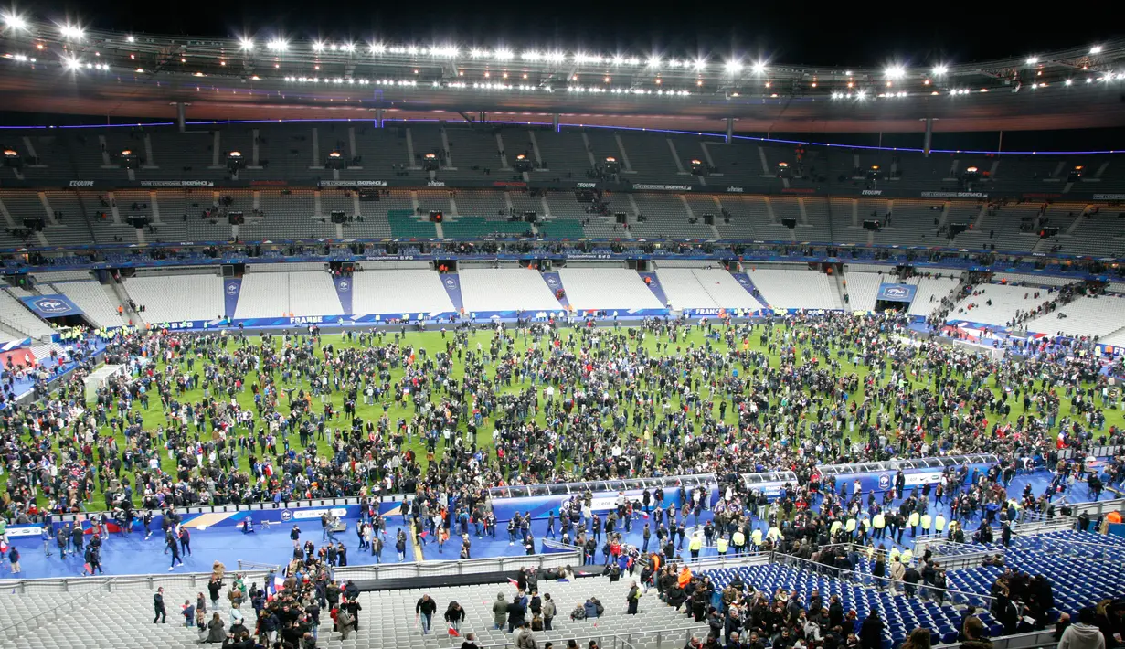 Ribuan Penonton berhamburan di lapangan stadion Stade de France saat menyaksikan pertandingan antara Prancis melawan Jerman di Saint-Denis, Paris, (13/11). Serangan bom terjadi di dekat stadion Stade de France Prancis. (AFP PHOTO/Matthieu ALEXANDRE)