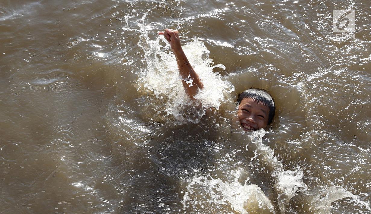 Seorang anak berenang di Kanal Banjir Barat, Jakarta, Jumat (23/3). Mahalnya biaya sewa kolam renang menyebabkan anak-anak berenang tidak pada tempatnya. (Liputan6.com/Immanuel Antonius)