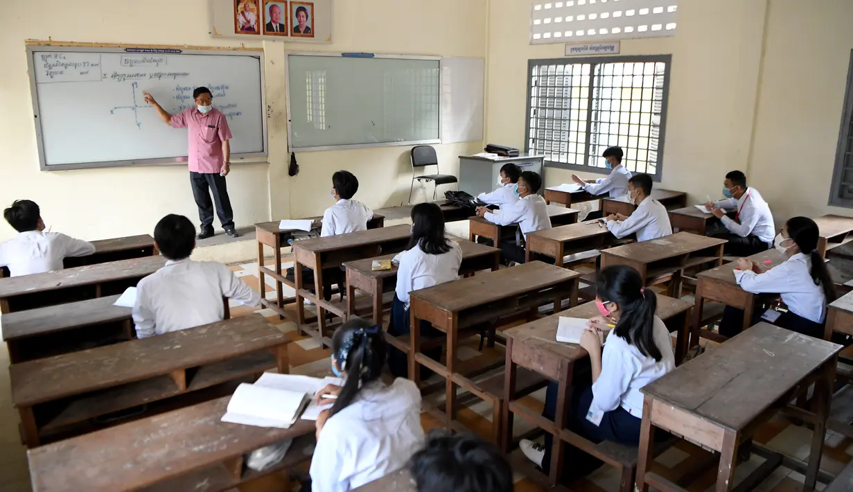 Siswa duduk di kelas dengan menjaga jarak saat memperhatikan guru mereka mengajar ketika sekolah dibuka kembali di Phnom Penh, Senin (7/9/2020). Sekolah-sekolah di Kamboja dibuka kembali pada Senin (7/9) setelah enam bulan ditutup akibat COVID-19. (TANG CHHIN Sothy /AFP)