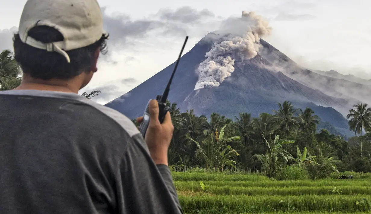 Seorang relawan menggunakan walkie talkie-nya saat memantau Gunung Merapi saat erupsi di Sleman (27/1/2021). Sekitar 150 warga di lereng barat daya Gunung Merapi di Kabupaten Sleman, DIY, mengungsi dari rumah, Rabu (27/1/2021) sore. (AP Photo/Slamet Riyadi)