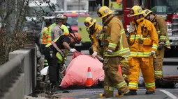 Penyidik melihat mayat korban akibat tabrakan antara dua truk besar di utara pusat kota Los Angeles (25/4). Kecelakaan ini menewaskan satu orang dan melukai sejumlah orang lainnya. (AP Photo/Reed Saxon)