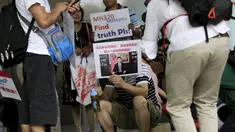 Salah satu keluarga penumpang MH370 membawa poster saat menggelar aksi di depan kantor Malaysia Airlines, Beijing, Kamis (6/8). Pemerintah Malaysia telah resmi menyatakan puing pesawat di Pulau Reunion adalah bagian dari MH370. (REUTERS/Jason Lee)