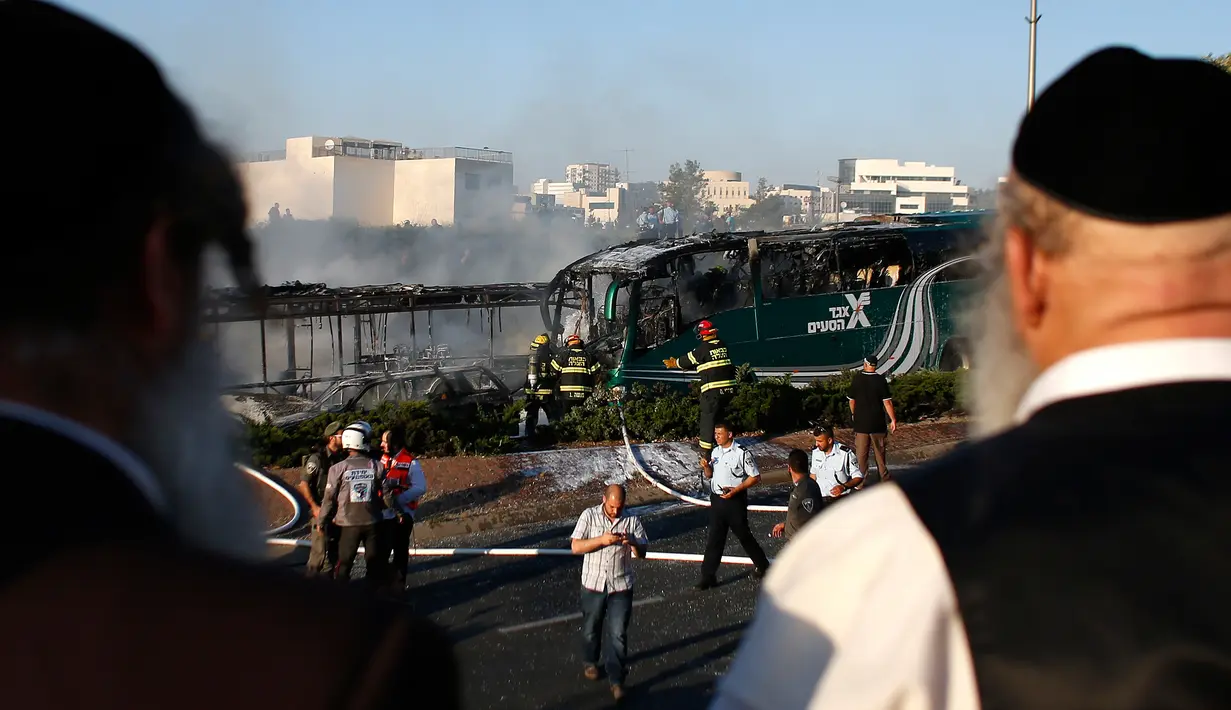 Warga melihat lokasi meledaknya sebuah bom di bus yang berada Yerusalem, Israel, Senin (18/4). Insiden itu membuat bus terbakar dan melukai 16 orang. (Ahmad GHARABLI/AFP)