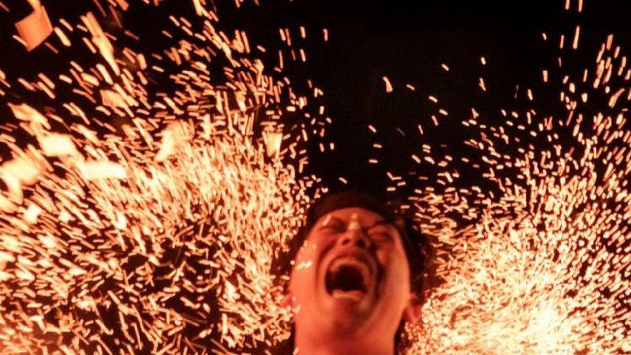 Reaksi salah satu pria Hindu saat menahan pukulan daun kelapa yang membara. Foto: Yasuyoshi CHIBA / AFP
