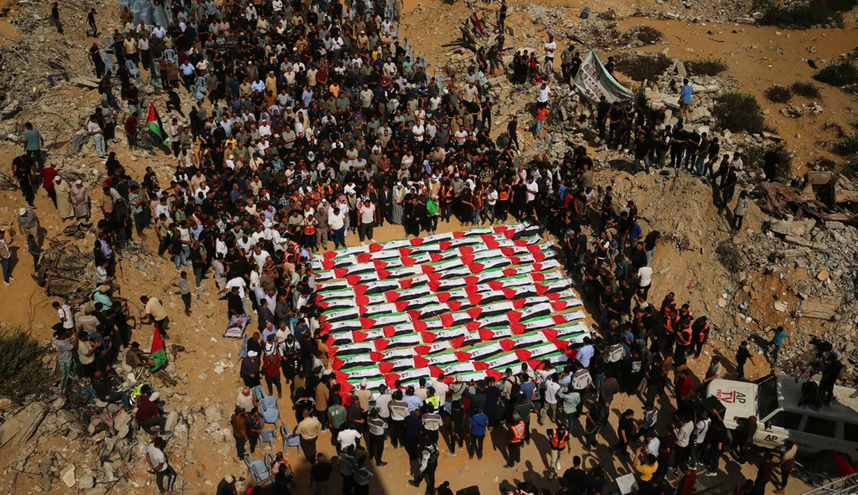 Warga Palestina berkumpul di sekitar jenazah warga Palestina yang tewas dalam serangan Israel selama perang dengan Hamas setelah ditemukan dari bawah reruntuhan bangunan, dalam prosesi pemakaman di Kota Gaza, Kamis (1/10/2026). Jenazah yang ditutupi bendera Palestina tersebut diiringi keluarga dan warga dalam suasana duka. (AP Photo/Yousef Al Zanoun)