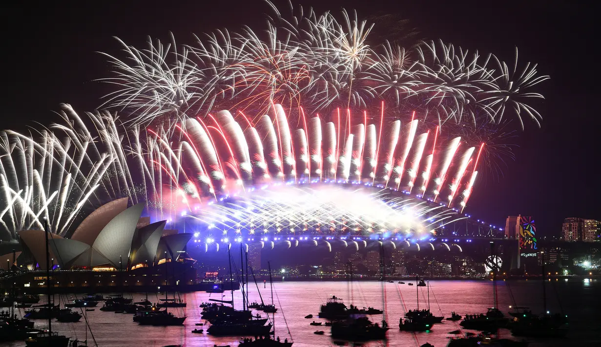 Kembang api menghiasi langit di atas Gedung Opera dan Jembatan Harbour saat pergantian tahun di Sydney (01/1/2018). Sekitar 10 ribu jenis efek menghiasi Opera House dan Sydney Harbour Bridge. (AFP Photo / Saeed Khan)