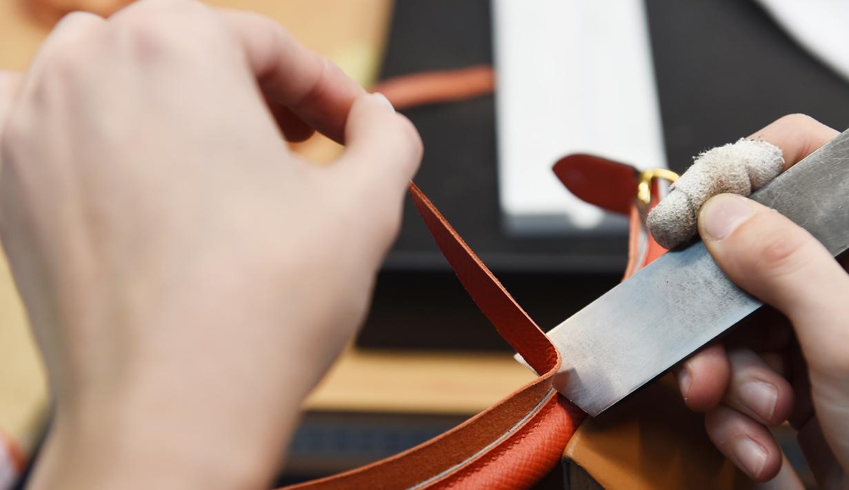 Seorang pengrajin memotong bagian tas saat bekerja di bengkel produsen barang-barang mewah Hermes di Allenjoie, Perancis, Kamis (5/4). Tas Hermes seolah menjadi simbol gaya hidup bagi kaum sosialita di dunia. (SEBASTIEN BOZON/AFP)