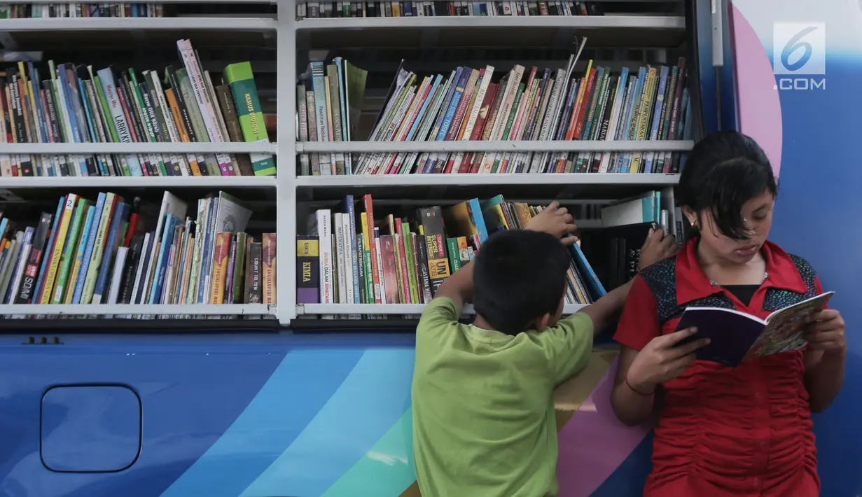 Seorang anak membaca buku di mobil Perpustakaan Keliling di Klungkung, Bali, Sabtu (30/09). Perpustakaan Keliling ini hadir untuk memberikan hiburan bagi korban Gunung Agung khususnya anak-anak.  (Liputan6.com/Gempur M Surya)