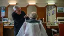 Penata rambut Roger Amilhastre (kiri), 90 tahun, memotong rambut Yves Desdoit di salon rambutnya, "Achillle coiffure masculin", di kota Saint-Girons, barat daya Prancis pada 16 April 2024. (Photo by Ed JONES / AFP)