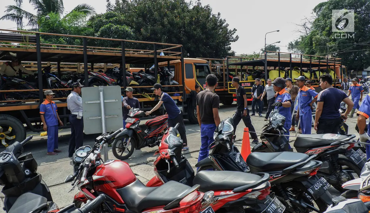 Petugas menaikkan sepeda motor milik peserta program mudik gratis dari Pemprov DKI Jakarta ke atas truk sebelum diberangkatkan di Terminal Pulogadung, Rabu (29/5/2019). Sebanyak 712 motor akan di kirim ke 10 kota tujuan pada tahap pertama Mudik Gratis Pemprov DKI 2019. (Liputan6.com/Faizal Fanani)