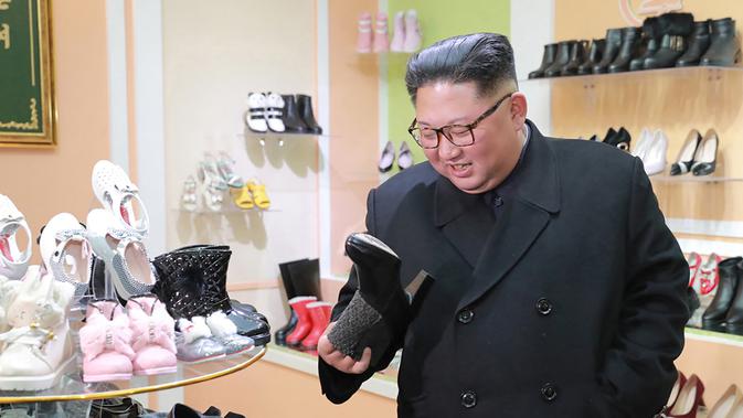Pemimpin Korea Utara, Kim Jong-Un melihat salah satu sepatu saat mengunjungi pabrik sepatu Wonsan, Korea Utara (3/12). (Photo by KCNA VIA KNS / various sources / AFP)