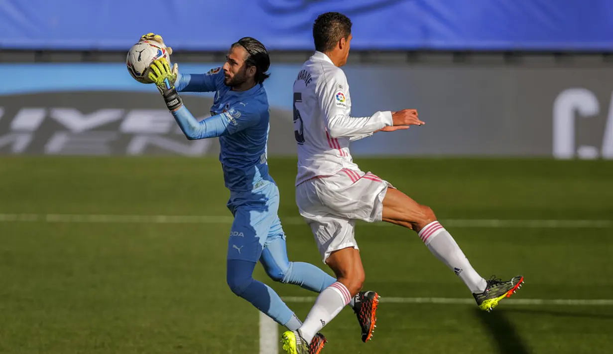 Kiper Valencia Jaume Domenech (kiri) menangkap bola di samping pemain Real Madrid Raphael Varane pada pertandingan Liga Spanyol di Stadion Alfredo Di Stefano, Madrid, Spanyol, Minggu (14/2/2021). Madrid geser Barcelona di peringkat dua klasemen usai menaklukkan Valencia. (AP Photo/Manu Fernandez)