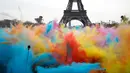 Pemandangan ketika sejumlah orang melempar bubuk berwarna saat merayakan akhir perlombaan Color Run 2018 di depan Menara Eiffel di Paris, Prancis (15/4). Dengan acara ini sekitar Menara Eiffel terlihat berwarna-warni. (AP/Thibault Camus)