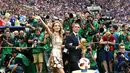 Mantan kapten Jerman Philipp Lahm (kanan) dan model Rusia Natalia Vodianova (kiri) menyapa penonton dengan membawa trofi Piala Dunia pada penutupan Piala Dunia 2018 Rusia di Stadion Luzhniki, Moskow (15/7). (AFP Photo / Franck Fife)