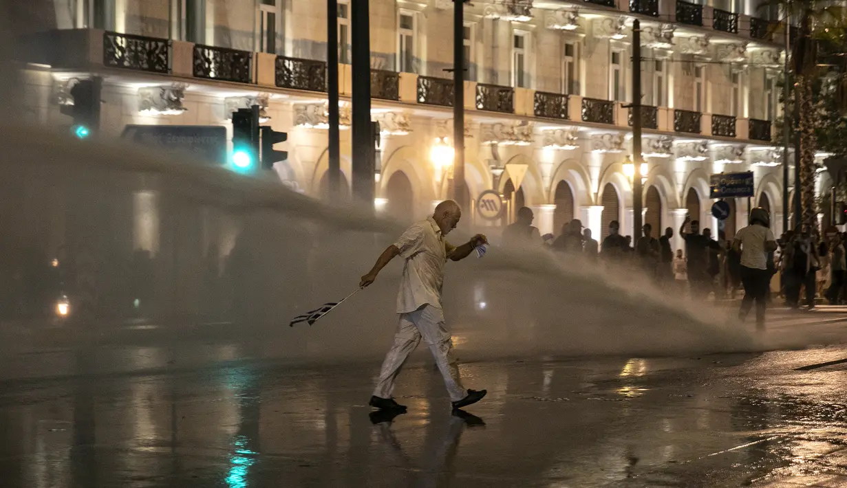 Polisi Yunani menggunakan meriam air untuk membubarkan pengunjuk rasa anti-vaksin selama rapat umum di alun-alun Syntagma, Athena tengah (24/7/2021). Yunani ukses dalam program vaksinasi corona. Saat ini, sekitar 50% dari 11 juta populasi telah divaksinasi lengkap. (AP Photo/Yorgos Karahalis)