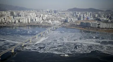 Sebuah kapal penumpang (bawah) menyeberangi aliran es di Sungai Han yang membeku di Seoul, Korea Selatan, Senin (25/1). Sungai Han membeku akibat suhu di Korea yang kini mencapai minus dol derajat Celsius. (REUTERS/Kim Hong - Ji)