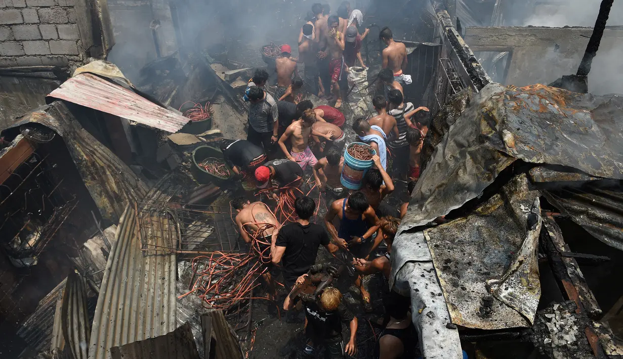Warga berdesakan untuk mengumpulkan sisa kabel listrik serta barang yang masih terpakai usai kebakaran pemukiman padat penduduk dekat pelabuhan di Manila, Filipina, Selasa (9/5). Mereka berebut mengumpulkan tembaga dari sisa kabel listrik (TED ALJIBE/AFP)