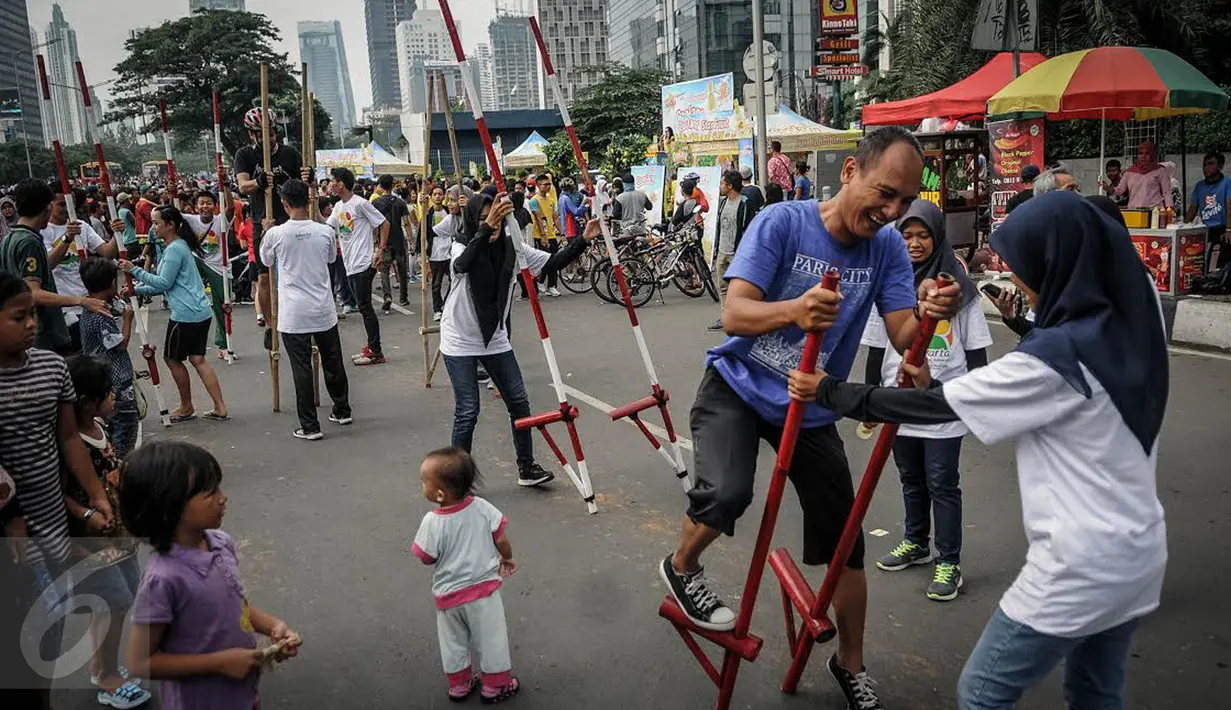 Seorang warga mencoba bermain Egrang saat demo ragam olahraga rekreasi TAFISA Games 2016 di kawasan Car Free Day Thamrin, Jakarta, Minggu (25/9). Kegiatan itu mengajak masyarakat untuk kembali mengenal permainan tradisional. (Liputan6.com/Faizal Fanani)