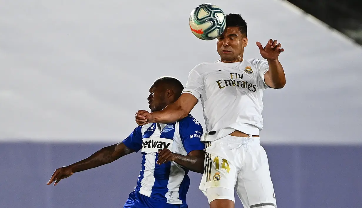 Gelandang Real Madrid, Casemiro melompat saat berbeut bola dengan pemain tengah Alaves, Jose Luis Rodriguez pada lanjutan Liga Spanyol di stadion Alfredo di Stefano, Sabtu (11/7/2020). Real Madrid menang 2-0 lewat gol Karim Benzema dan Marco Asensio. (GABRIEL BOUYS/AFP)
