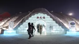 Foto yang diambil 13 Januari 2020, orang-orang keluar dari iglo seusai menikmati hot pot di meja dan kursi berukir es selama Festival Es dan Salju Internasional Harbin tahunan.  Restoran berbentuk rumah salju bangsa Eskimo ini hadir untuk memberikan sensasi makan malam yang berbeda. (STR/AFP)