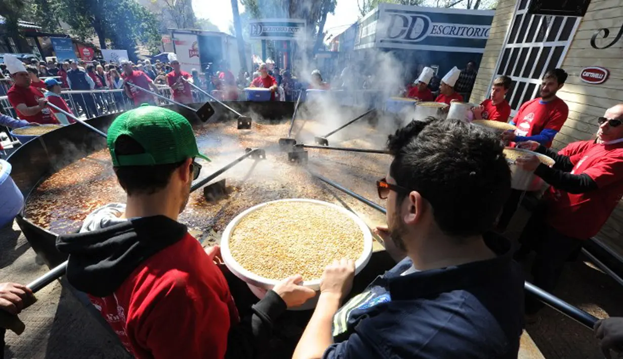 Koki bersiap menuangkan kacang lentil rebus ke panci raksasa untuk memecahkan rekor dunia Guinness Record dalam acara Prado Rural di Montevideo, Uruguay, Minggu (13/9/2015). Kacang tersebut cukup untuk memberi makan 10.000 orang. (AFP PHOTO/Miguel Rojo)