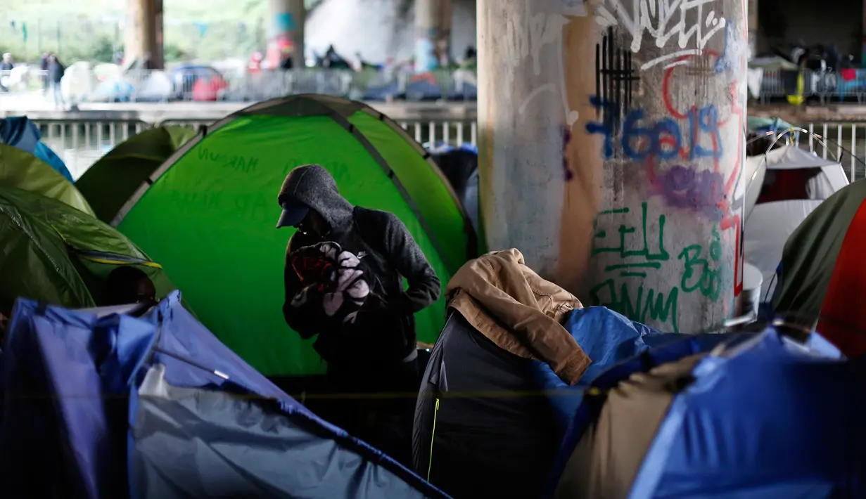 Seorang pria berada di sekitar tenda sementara di samping kanal di Paris, Prancis (30/5). Kamp bawah jembatan di Paris ini sudah sering dibersihkan, namun para pendatang asing kembali menempati tempat tersebut. (AP/Thibault Camus)