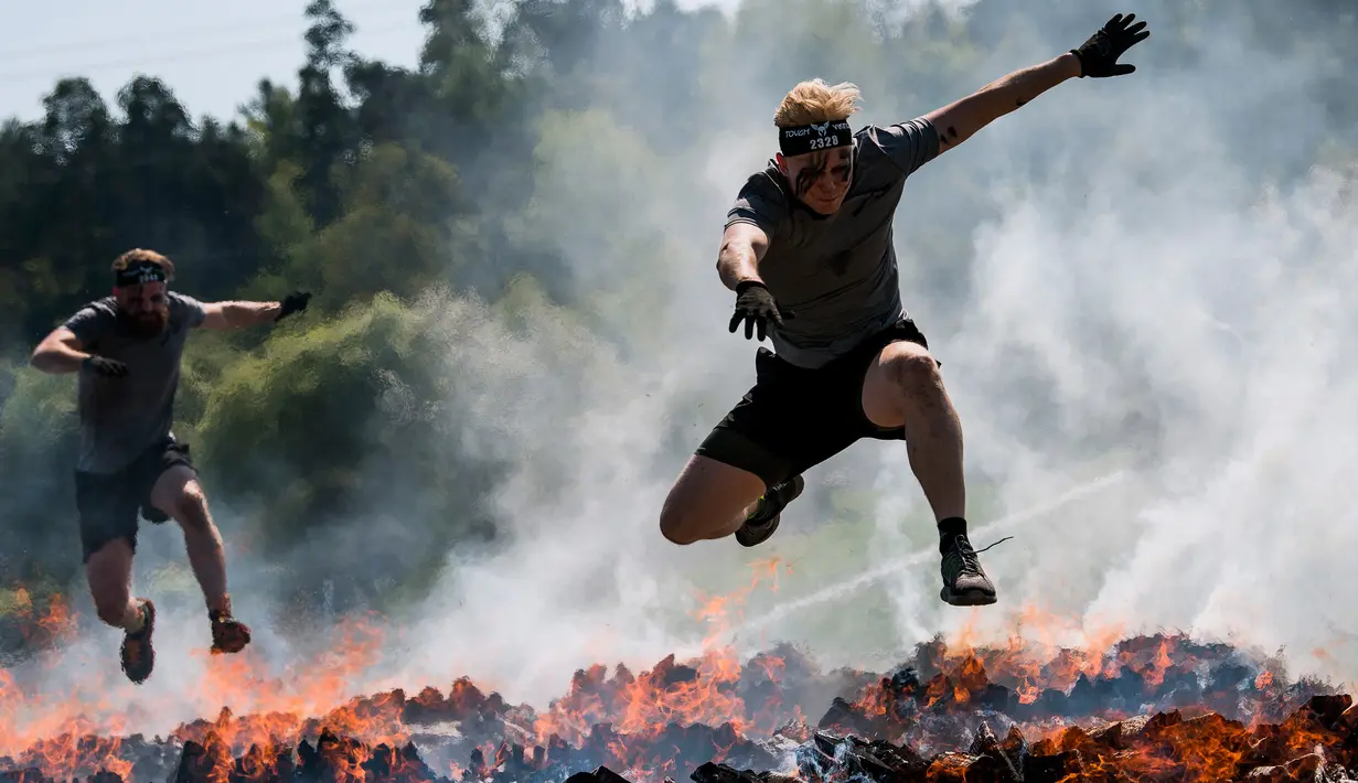 Dua pria menyeberangi rintangan api saat mereka mengikuti kompetisi Tough Viking di Stockholm, Swedia (12/5). Dalam lomba ini peserta harus menempuh jarak 8 km dengan 26 rintangan berat. (AFP/Jonathan Nackstrand)