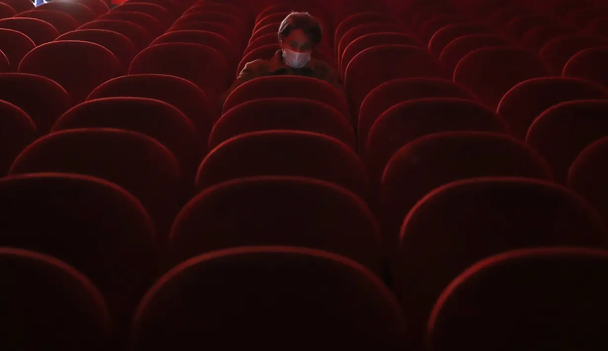 Seorang perempuan memakai masker saat dia menunggu untuk menonton film di dalam aula bioskop Beltrade, di Milan, Senin (26/4/2021). Italia kembali dibuka secara bertahap pada hari Senin setelah enam bulan memberlakukan lockdown untuk menghambat penyebaran Covid-19. (AP Photo/Antonio Calanni)