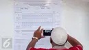 Petugas mengambil gambar hasil perhitungan suara Pilkada DKI 2017 di TPS 17, Petamburan, Tanah Abang, Jakarta, Rabu (19/4). Pasangan nomor urut 2, Ahok-Djarot unggul tipis dari pasangan nomor 3, Anies-Sandi. (Liputan6.com/Gempur M Surya)
