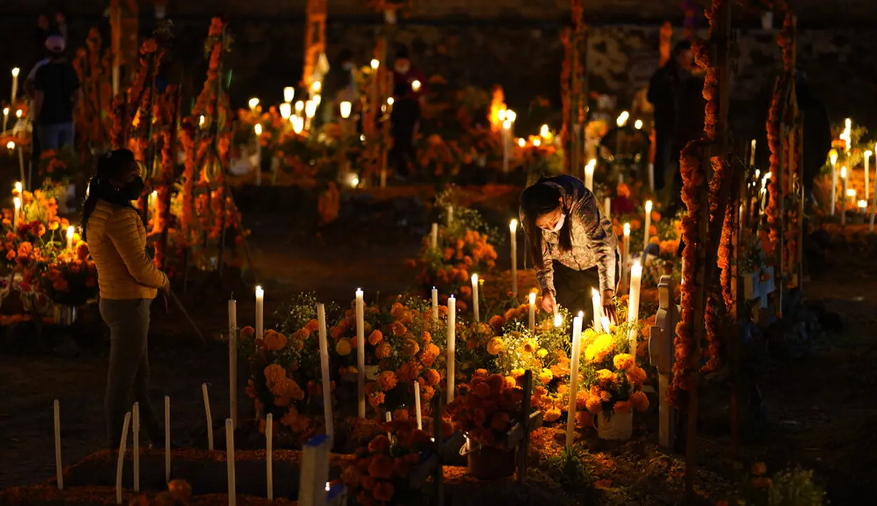 Kerabat bersiap bermalam di samping makam orang tercinta pada perayaan Hari Kematian di pemakaman Arocutin, Michoacan, Meksiko, 1 November 2021. Dalam tradisi ini keluarga menghias makam serta bermalam di kuburan menemani orang tercinta yang telah meninggal. (AP Photo/Eduardo Verdugo)