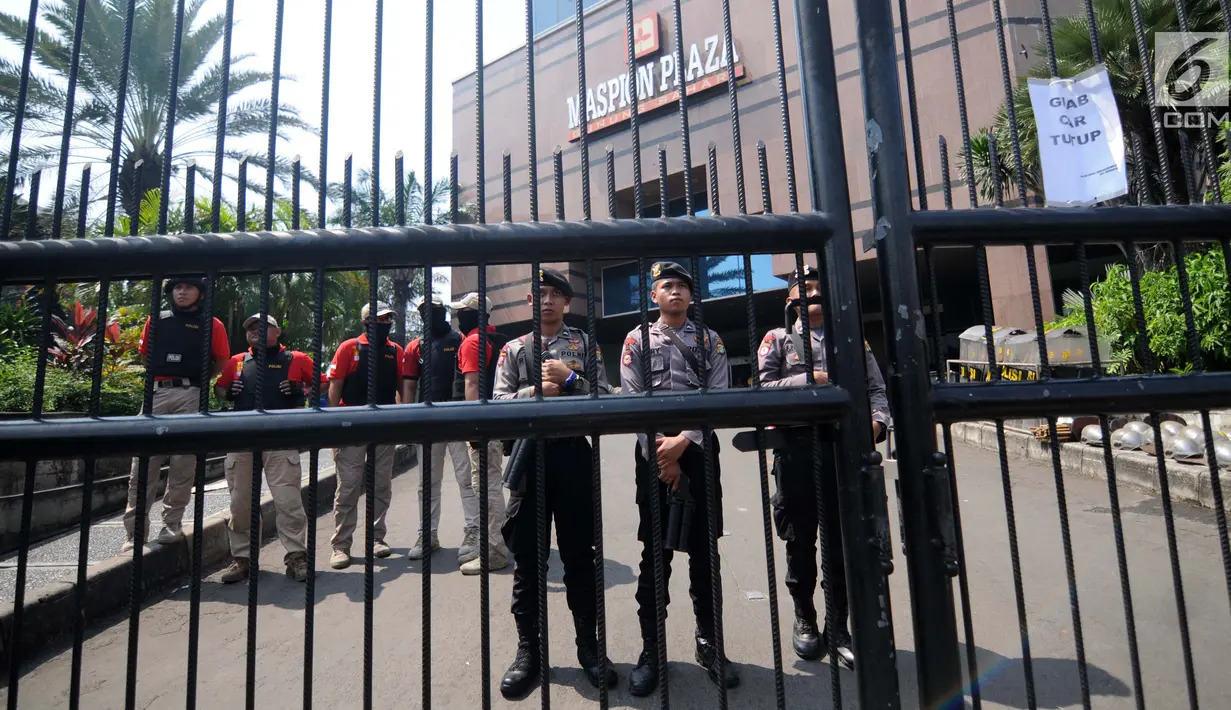 Petugas polisi berjaga di depan Gedung Maspion Plaza, Jakarta Utara, Selasa (4/7). Mereka mununtut pihak Grab untuk mencairkan bonus Lebaran 2017 yang dijanjikan pihak perusahaan jika tetap bekerja selama libur Lebaran. (Liputan6.com/Gempur M Surya)