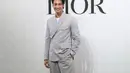 Apo tampak kenakan Double-Breasted Jacket with Buttoned Strap seharga Rp62jutaan. Dipadu dengan celana abu-abu dan sneakers putih dari Dior