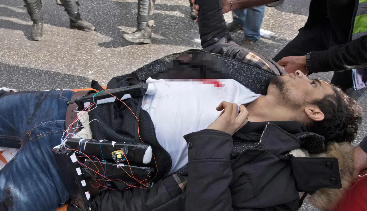 Seorang pria Palestina yang dicurigai mengenakan rompi bom bunuh diri dibawa ke sebuah ambulans setelah dia ditembak polisi Israel karena menikam seorang tentara di kota al-Bireh, Tepi Barat yang diduduki Israel (15/12). (AFP Photo/Oren Ziv)