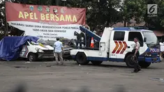 Petugas Ditlantas Polda Metro Jaya membawa mobil dinas polisi di Mapolsek Ciracas, Jakarta, Rabu (12/12). Ditlantas Polda Metro Jaya mengevakuasi sejumlah mobil yang rusak akibat penyerangan Polsek Ciracas. (Liputan6.com/Herman Zakharia)