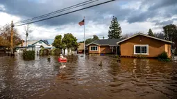 Banjir akibat badai mengelilingi rumah di Thornton Rd, Merced, California, Amerika Serikat, 10 Januari 2023. Serangkaian badai yang menghantam California telah menyebabkan jalanan terendam banjir, gelombang tinggi air laut, sungai meluap, dan memaksa ribuan orang untuk mengungsi. (AP Photo/Noah Berger)