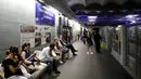 Para komuter duduk dekat tanda yang bertuliskan "Deschamps - Elysees Clemenceau" di stasiun metro Champs - Elysees Clemenceau, Paris, Senin (16/7). Hal itu untuk merayakan kesuksesan timnas Prancis menjadi juara Piala Dunia. (AFP/Thomas SAMSON)