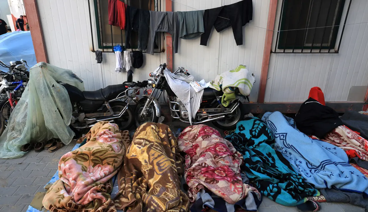 Berjejalan di bawah tenda darurat di tempat parkir mobil, tidur di koridor atau di tangga, melewatkan waktu seharian di tangga, menggantung cucian di atap – ribuan pengungsi Gaza memenuhi setiap ruang di Rumah Sakit Al Shifa. (Mahmud HAMS / AFP)