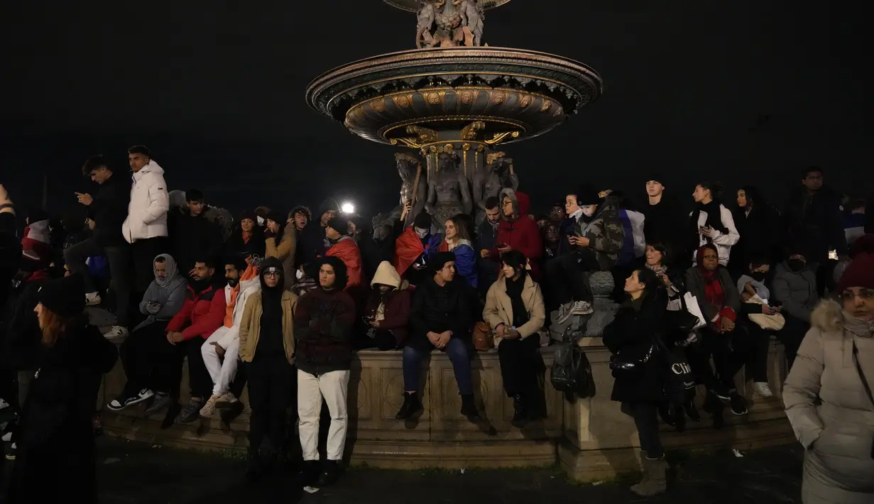 Para suporter duduk di air mancur menunggu para pemain Prancis tiba di Hotel Crillon di Paris, Senin, 19 Desember 2022. Prancis yang gagal mempertahankan gelar Piala Dunia tetap mendapat sambutan para suporter ketika tiba di Paris pada Senin (19/12) malam waktu setempat. (AP Photo/Francois Mori)