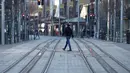 Seorang pria melintasi jalan yang sepi di Sydney (21/8/2021). Kota itu memperpanjang penguncian selama dua bulan dan memberlakukan jam malam sebagian untuk menahan wabah virus corona yang menyebar cepat. (AFP/David Gray)