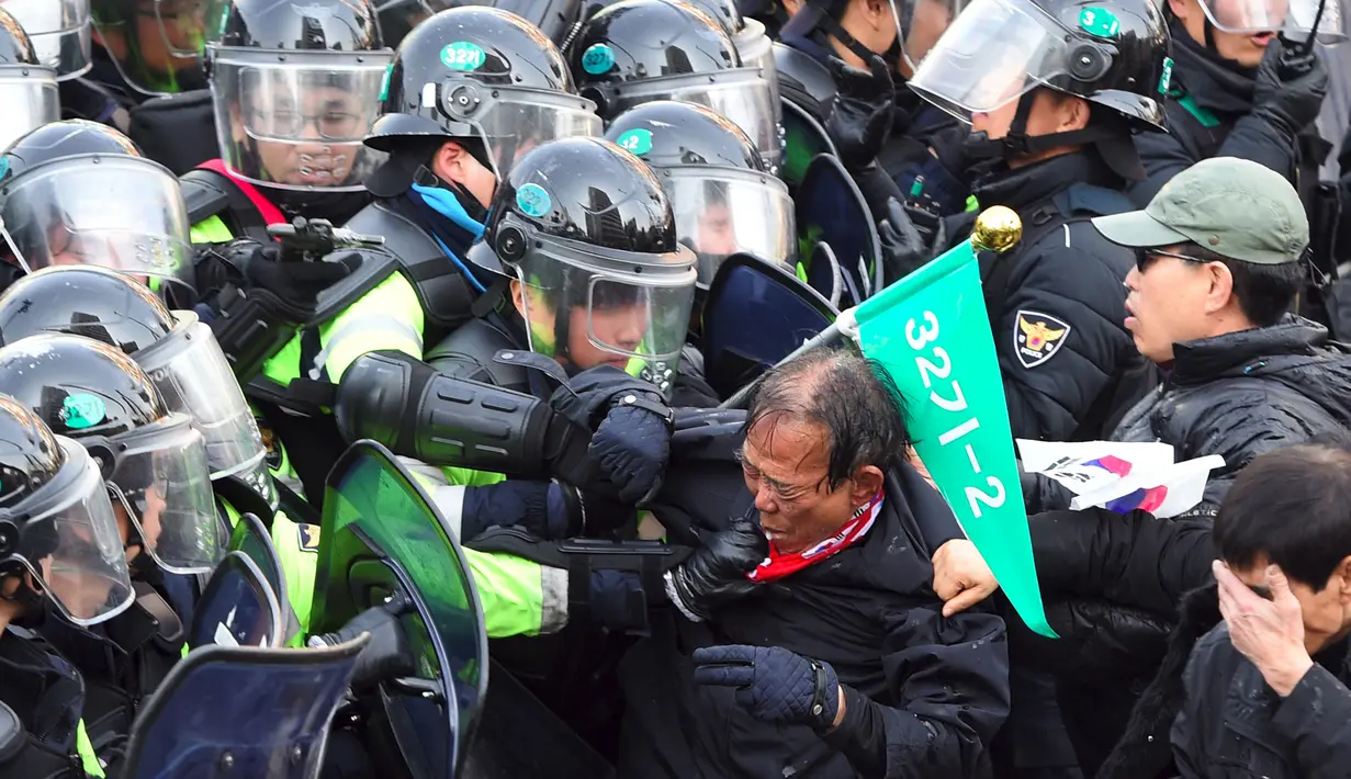 Pendukung Presiden Korea Selatan (Korsel), Park Geun-hye terlibat bentrok dengan aparat polisi di Seoul, Jumat (10/3). Pemakzulan Presiden Park yang dikeluarkan Mahkamah Konstitusi memicu aksi unjuk rasa yang berakhir bentrokan. (JUNG Yeon-Je/AFP)