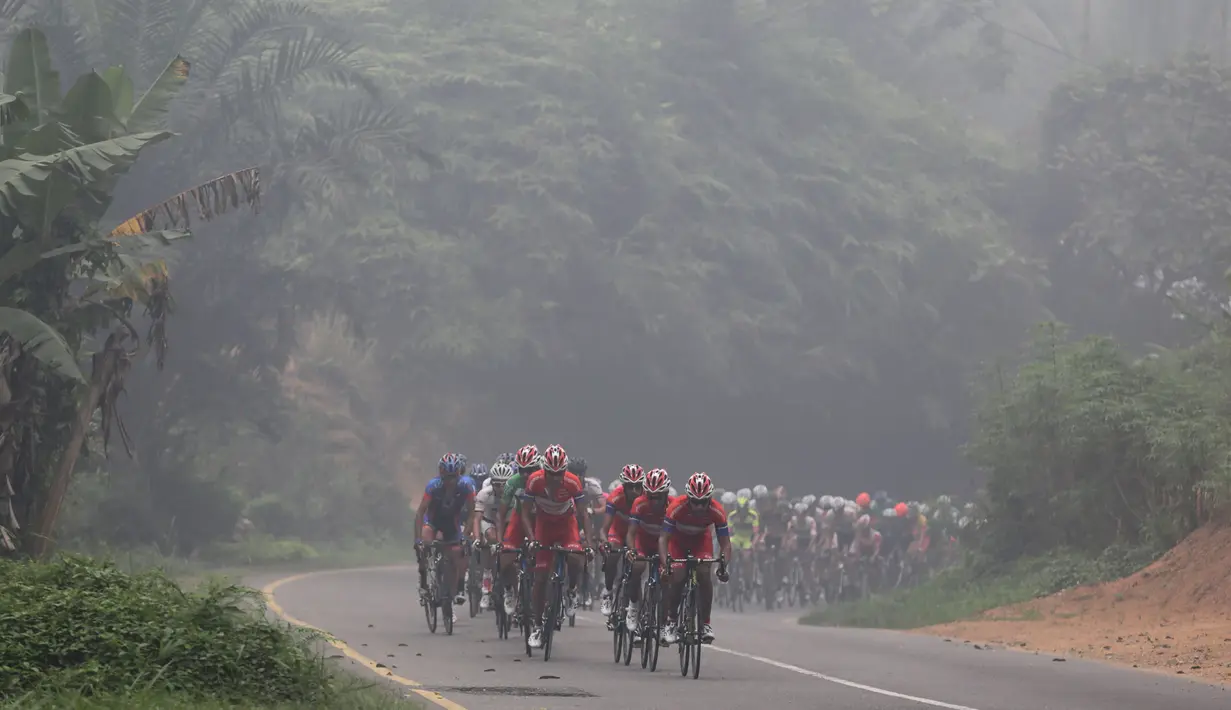 Kabut asap pekat sepanjang lintasan mengiringi perjalanan para pebalap di Etape 3 Tour de Singkarak 2015 antara Sijunjung menuju Dharmasraya, Sumatra Barat, Senin (5/10/2015). (Bola.com/Arief Bagus)