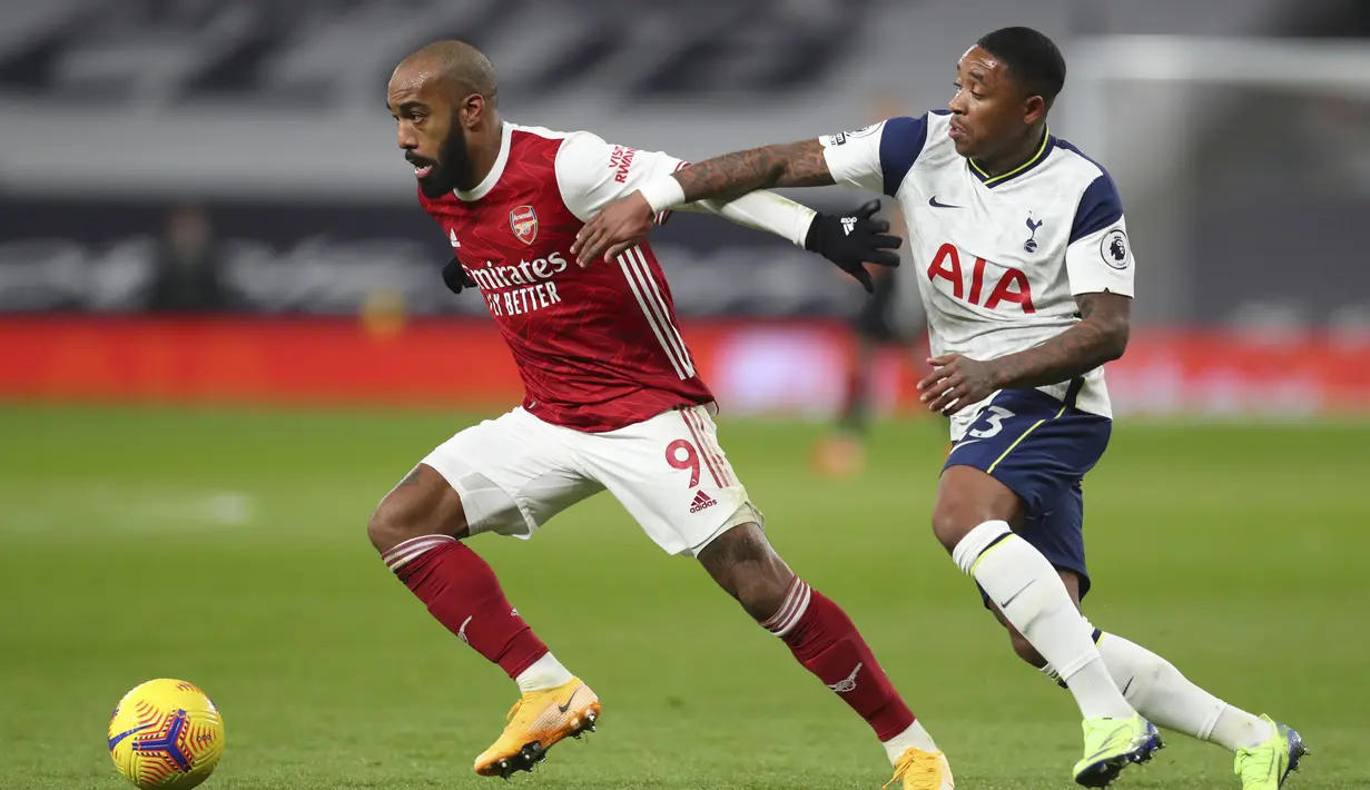 Penyerang Arsenal, Alexandre Lacazette (kiri) membawa bola dari kawalan penyerang Tottenham Hotspur, Steven Bergwijn pada pertandingan lanjutan Liga Inggris di Tottenham Hotspur Stadium di London, Inggris , Minggu (7/12/2020). Tottenham menang 2-0. (Catherine Ivill/Pool via AP)